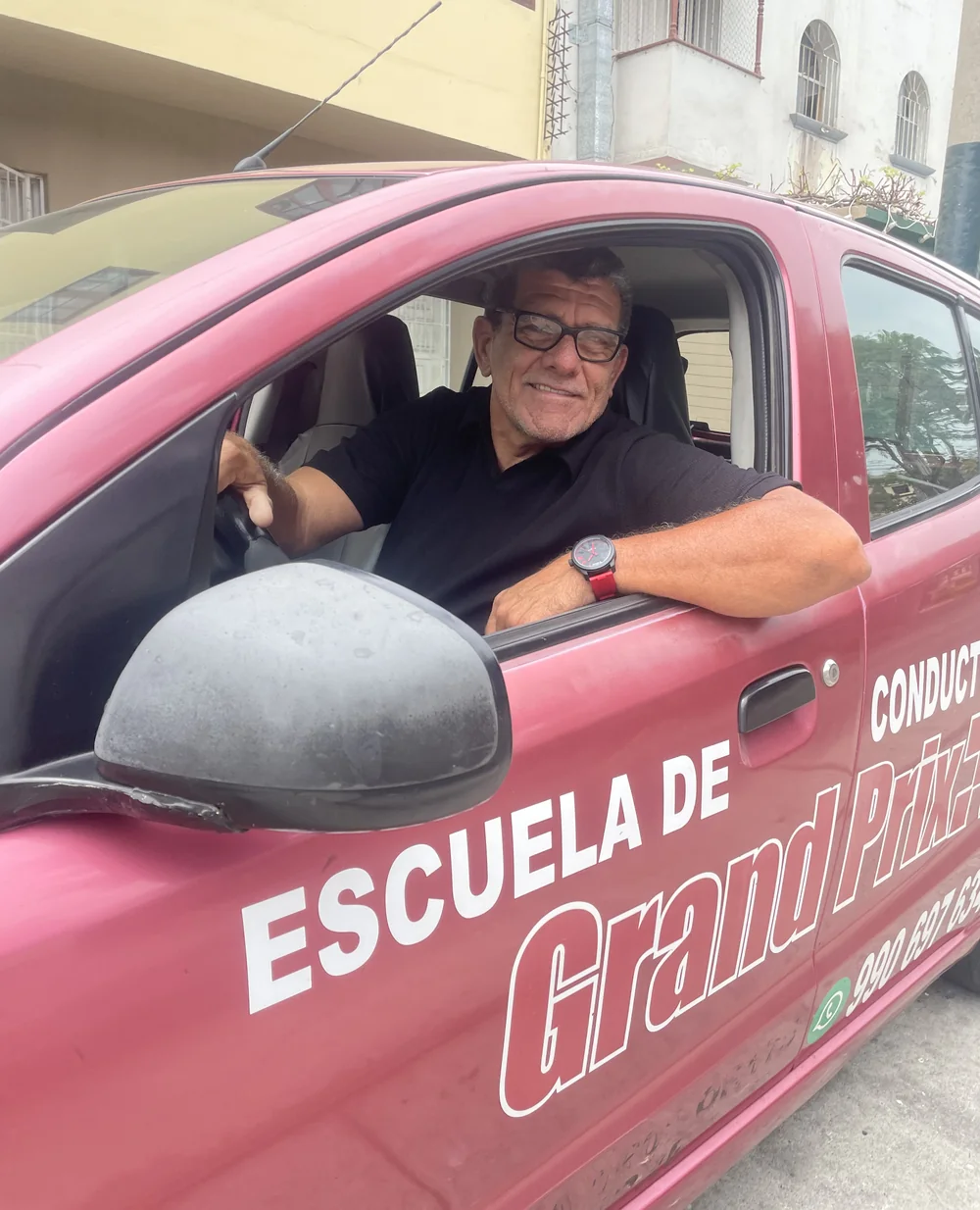 Instructor de Grand Prix sonriendo al volante del auto rosado de la escuela